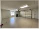 Spacious garage with epoxy flooring, storage, garage door opener, and natural light from window at 6307 Se 8Th Ln, Ocala, FL 34472