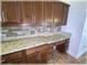 Kitchen countertop with granite counters, wood cabinets, stone backsplash, and a desk area at 6307 Se 8Th Ln, Ocala, FL 34472