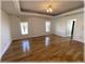 Spacious living room featuring wood floors, crown molding, and two windows with light colored curtains at 6307 Se 8Th Ln, Ocala, FL 34472
