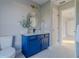 Bathroom featuring blue vanity, round mirror, and tiled floors, with an open doorway to another room at 75 Pine Crse, Ocala, FL 34472