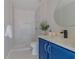 Bright bathroom featuring a blue vanity, round mirror, and a step-in shower with white tile at 75 Pine Crse, Ocala, FL 34472