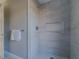 The white tiled shower features a niche, modern fixtures and a showerhead at 75 Pine Crse, Ocala, FL 34472