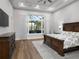 Bright main bedroom with tray ceiling, hard floors, and a large window overlooking the backyard at 7635 Nw 33Rd Pl, Ocala, FL 34482