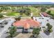 An aerial view of the clubhouse with a golf course and driving range beyond the parking lot in the background at 9886 Se 178Th Ln, Summerfield, FL 34491