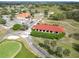 Aerial of red roofed buildings on the golf course surrounded by green fairways and tree lined roads at 9886 Se 178Th Ln, Summerfield, FL 34491