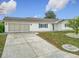 Single-story home with white siding, grey roof, and a spacious driveway, surrounded by grass and landscaping at 9886 Se 178Th Ln, Summerfield, FL 34491