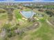 Scenic aerial view of the golf course, with a heart shaped pond, sand traps, and golf carts traversing the landscape at 9886 Se 178Th Ln, Summerfield, FL 34491