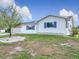 Side view of a cozy single-story home featuring white siding and purple shutters, surrounded by green grass at 9886 Se 178Th Ln, Summerfield, FL 34491