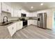 Modern kitchen featuring stainless steel appliances, granite countertops, and white cabinets, with gray wood-look flooring at 1370 Sw Obee Ridge Rd, Dunnellon, FL 34432