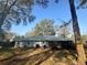 View of the home from the backyard showcasing mature trees and a patio area at 13949 Se 53Rd Ave, Summerfield, FL 34491