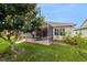 Backyard view of the patio area with mature trees, landscaping and lawn at 17959 Se 89Th Natchez Ave, The Villages, FL 32162