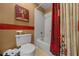 Bathroom with white tiled shower/bathtub, red accents, neutral walls, and a toilet with ample storage space at 1902 Se 37Th Court Cir, Ocala, FL 34471