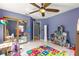 Bright bedroom with tile flooring, ceiling fan, a large mirror closet and colorful playmat at 3621 Sw 52Nd Ter, Ocala, FL 34474