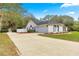 Extended driveway leads to a charming home with a two-car garage, set among lush trees and manicured landscaping at 3621 Sw 52Nd Ter, Ocala, FL 34474