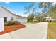 Side of home featuring a two-car garage and a well-maintained yard with mature greenery and a long driveway at 3621 Sw 52Nd Ter, Ocala, FL 34474