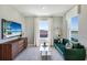 Bright living room featuring a comfortable green sofa, sleek wooden dresser, and large windows at 4250 Sw 53Rd Lane Rd, Ocala, FL 34474