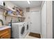 Bright laundry room with a washer, dryer, sink, storage shelves, and access door to the exterior at 4320 Sw 112Th St, Ocala, FL 34476
