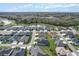 An aerial view shows a community situated around a serene pond and surrounded by trees at 4384 Pezzullo Cir, The Villages, FL 32163