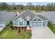 Aerial view of a well maintained single Gathering home featuring mature trees, a pond, and a three car garage at 4384 Pezzullo Cir, The Villages, FL 32163