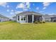 Expansive backyard featuring a well-maintained lawn, lush landscaping, and a screened-in lanai at 4384 Pezzullo Cir, The Villages, FL 32163