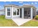 Corner view of the home's exterior showcasing a concrete patio and screened-in porch with large windows at 4384 Pezzullo Cir, The Villages, FL 32163