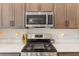 Stainless steel microwave above a gas range stove surrounded by white quartz countertops and stylish lighting at 4384 Pezzullo Cir, The Villages, FL 32163