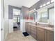 Bathroom featuring double sinks, large mirror, and a tiled shower with glass doors at 5111 Nw 35Th Pl, Ocala, FL 34482