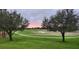 Scenic golf course view featuring lush green grass, trees, sand traps, and a beautiful sunset sky at 5111 Nw 35Th Pl, Ocala, FL 34482