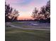 Scenic view of the manicured golf course with sand trap and path, framed by trees at sunset at 5111 Nw 35Th Pl, Ocala, FL 34482