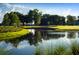 Scenic view of a golf course with a serene pond, mature trees, and lush green grass at 5111 Nw 35Th Pl, Ocala, FL 34482