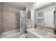 Well-lit bathroom featuring wood tile accent wall, modern vanity and a shower-tub combination at 530 Nw 113Th Cir, Ocala, FL 34482