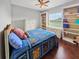 Cozy bedroom with hardwood floors, built-in shelves, and a window overlooking the backyard at 5725 Ne 31St Ter, Ocala, FL 34479