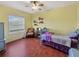 Comfortable yellow bedroom with a ceiling fan and wood floors at 5725 Ne 31St Ter, Ocala, FL 34479