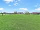 A large green lawn highlights the front of this lovely home set beneath a bright, cloudy sky at 5725 Ne 31St Ter, Ocala, FL 34479