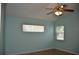 Serene bedroom painted in light blue, featuring natural light from two windows and a ceiling fan at 6548 Sw 84Th Place Rd, Ocala, FL 34476