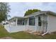 Exterior view shows the home with a covered patio, white vinyl fence and manicured lawn at 6548 Sw 84Th Place Rd, Ocala, FL 34476