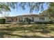A backyard with the rear of the house, a screen door and lush foliage at 8740 Se 140Th Place Rd, Summerfield, FL 34491