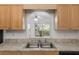 Kitchen sink area showcasing light wood cabinets and a window offering natural light and views of greenery at 8740 Se 140Th Place Rd, Summerfield, FL 34491