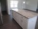Kitchen island with granite countertop, white cabinets, and stainless steel hardware, with hard wood floors at 9455 Se 152Nd Pl, Summerfield, FL 34491