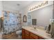 Well-lit bathroom with a single sink, wood cabinetry, and a shower featuring a patterned curtain at 9710 Sw 96Th St, Ocala, FL 34481
