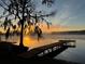 Scenic lake view with a wooden pier at sunrise, providing a serene and picturesque setting at 1192 Ne 130Th Ter, Silver Springs, FL 34488