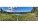 Panoramic view of tranquil pond surrounded by lush greenery and a clear blue sky, creating a serene natural setting at 1192 Ne 130Th Ter, Silver Springs, FL 34488