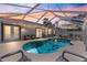 Inviting screened-in pool with patio, lounge furniture, and string lights offers backyard relaxation and entertaining at 1192 Ne 130Th Ter, Silver Springs, FL 34488