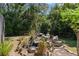 A decorative rock waterfall adds a touch of elegance to the serene, tree-lined backyard at 14721 Se 30Th Ct, Summerfield, FL 34491