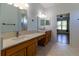 Bright bathroom with double sinks, wood cabinets, and view into bedroom at 15304 Sw 15Th Terrace Rd, Ocala, FL 34473