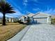 Well-manicured home with a two-car garage, expansive driveway, and mature palm tree in the yard at 15702 Sw 16Th Avenue Rd, Ocala, FL 34473