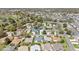 An aerial view shows a neighborhood with manicured lawns and mature trees near a golf course and waterway at 1854 Oxford Lane, The Villages, FL 32162