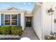 Close-up of the front door with blue shutters and manicured shrubs at 1854 Oxford Lane, The Villages, FL 32162