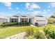 Charming single-story home with white siding, blue shutters, well-manicured lawn, and a two-car garage at 1854 Oxford Lane, The Villages, FL 32162