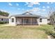 Back exterior view of a home featuring a screened porch and well-maintained yard at 1854 Oxford Lane, The Villages, FL 32162